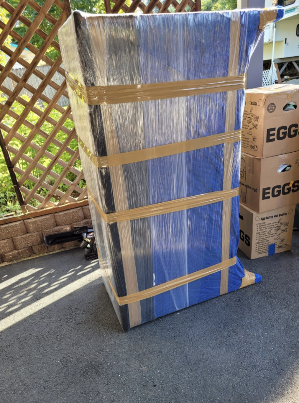 Cabinet padded and shrink wrapped, ready to load in a driveway